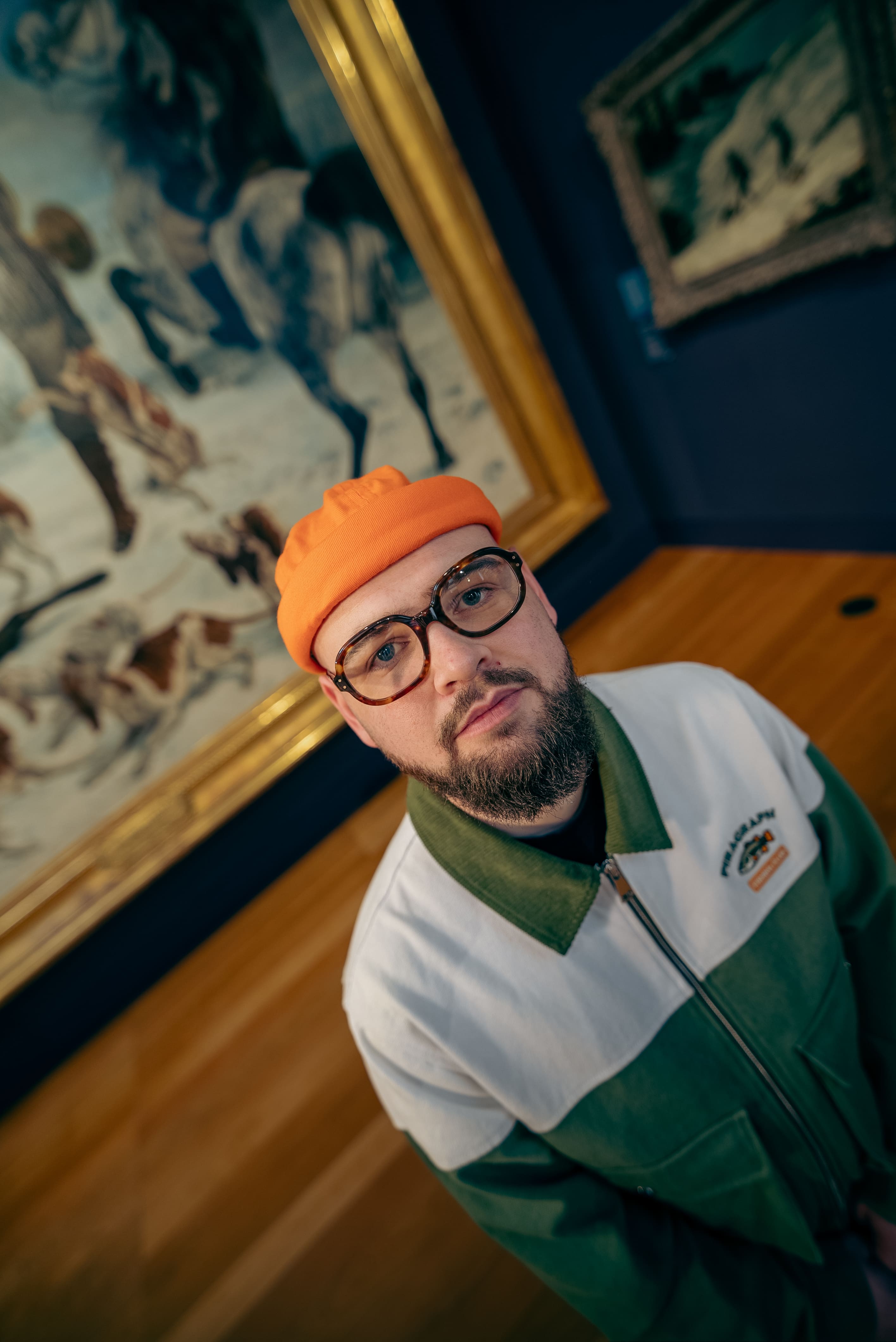 Portrait — monture écaille et casquette orange, salle de musée